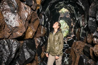 Femme explorant un tunnel de lave volcanique à La Réunion sous la pluie, activité géologique en intérieur