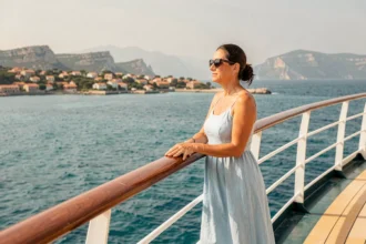 Femme sur le pont d'un bateau de croisière admirant la côte méditerranéenne