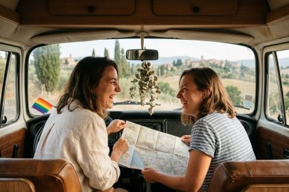 Deux femmes souriantes consultant une carte routière dans un van vintage lors d'un road trip LGBTQ+ en Europe